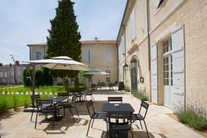 een patio met tafels en stoelen en een parasol bij College des Doctrinaires in Lectoure