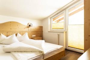 1 dormitorio con 1 cama con sábanas blancas y ventana en Bäckelar‘s Apart, en Sölden