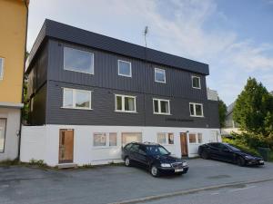 a black and white building with two cars parked in front at Lyngen Apartments in Lyngseidet