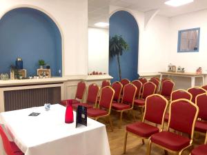 une salle à manger avec des chaises rouges, une table blanche et un chairsearcher dans l'établissement Le Clocher de Rodez Centre Gare, à Toulouse