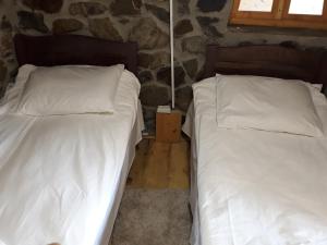 two beds in a room with a stone wall at Guest House Murkvam in Tvebishi