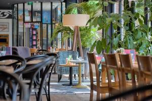 a restaurant with tables and chairs and plants at Hotel Theater Figi in Zeist