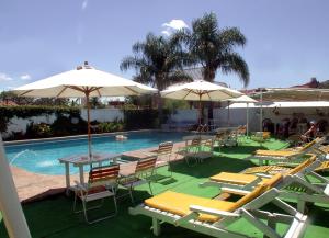 a swimming pool with lounge chairs and umbrellas at Hotel Capvio in Villa Carlos Paz