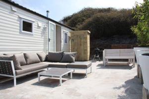 un patio con divano, tavolo e panca di Chalet De Duinberg a IJmuiden