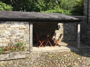 un refugio de piedra con una mesa y sillas. en The Stable Loft, Llwynhelig Manor en Llandeilo