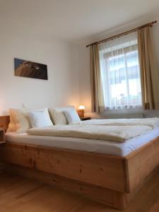a bedroom with a large wooden bed with a window at Tuschnhof in Rinn