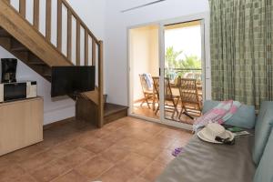 Il comprend un salon avec un canapé, une télévision et un balcon. dans l'établissement Vacancéole - Résidence Sognu di Mare, à Linguizzetta