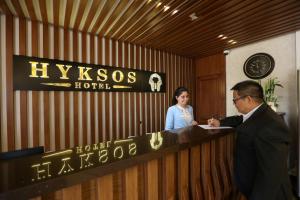 un homme et une femme debout derrière un comptoir de réception dans l'établissement Hyksos Hotel, à Erbil