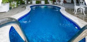 - une piscine avec de l'eau bleue et des chaises blanches dans l'établissement Hotel Mediterraneo Inn, à Santa Rosa de Lima