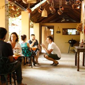 un groupe de personnes assises à des tables dans une pièce dans l'établissement Clayfingers Art Cottage, à Thrissur