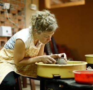 a woman is mixing something in a pot in a bowl at Clayfingers Art Cottage in Trichūr