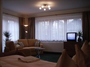 a hotel room with a bed and a couch and a television at Pension Heidi in Kaprun