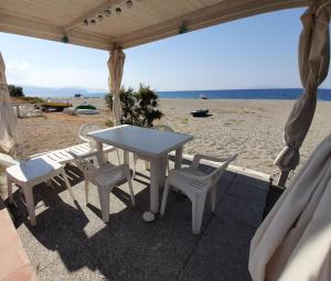 biały stół i krzesła na plaży w obiekcie Finestra sul Mare w mieście Terme Vigliatore