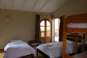 a bedroom with two beds and a window at Luna Rumi Hotel-Lodge Urubamba in Urubamba