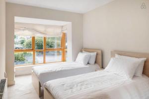 2 camas en una habitación blanca con ventana en Kelston South Dublin, en Dublín