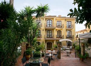 un bâtiment jaune avec des tables, des chaises et des arbres dans l'établissement Hotel Restaurante La Masieta, à Creixell