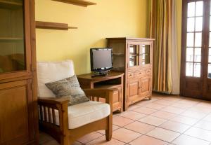 Cette chambre dispose d'une télévision, d'une chaise et d'un bureau. dans l'établissement Hotel Restaurante La Masieta, à Creixell