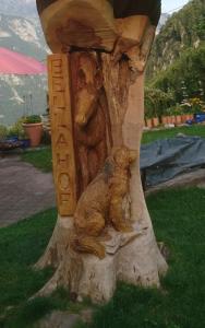 una estatua de un oso sentado en un tronco de árbol en Bellahof, en Flumserberg