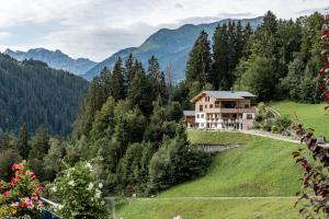 a house on a hill with mountains in the background at Appartement Mangeng in Bartholomäberg