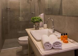 uma casa de banho com lavatório, toalhas e WC em Pousada Armazém 26 em Tiradentes