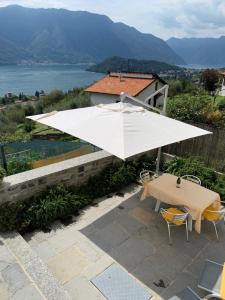 a large white umbrella on a patio with a table and chairs at La Filanda di Viano in Tremezzo