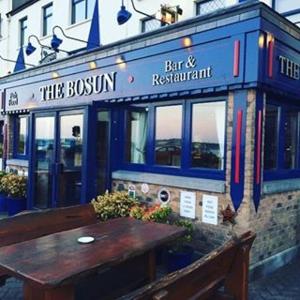 um bar e restaurante com uma mesa de madeira em frente em The Bosun em Monkstown