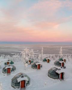 a group of huts in the snow with a sunset at Golden Crown - Levin Iglut in Levi