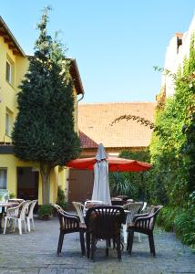 un patio con mesas, sillas y una sombrilla en Pension Damköhler Thale OT Westerhausen, en Thale