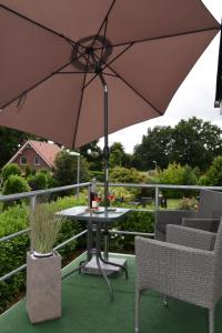 Ferienwohnung Storchennüst في أوريتش: طاولة وكراسي مع مظلة على شرفة