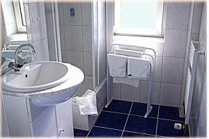 a white bathroom with a sink and a shower at Hotel Am Wehrhahn in Düsseldorf