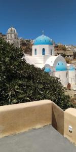 vista su un edificio con cupole blu di Santorinio Yellow House a Éxo Goniá