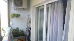 a window with a white curtain and a fan at Éva apartman in Balatonboglár