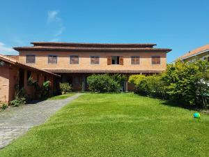 a house with a yard with a ball on the grass at Sol e Cia casa de temporada in Caraguatatuba