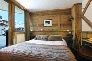 a bedroom with a wooden bed and a wooden wall at Hotel Des 3 Vallées Val Thorens in Val Thorens