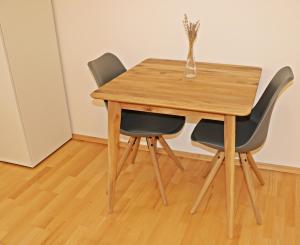 een houten tafel met twee stoelen en een vaas erop bij Fewo Burgunder in Hanhofen