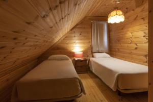 two beds in a room with wooden walls at Luna Chalets da Montanha - Serra da Estrela in Covilhã