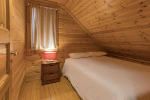 um pequeno quarto com uma cama e um candeeiro vermelho em Luna Chalets da Montanha - Serra da Estrela na Covilh