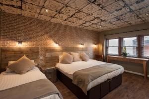a bedroom with two beds and a brick wall at City Retreat Edinburgh ApartHotels in Edinburgh