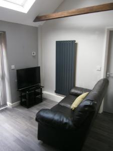 a black leather couch in a living room with a television at The Barn - Ilkeston - 1 Bedroom Flat, 2 Beds, Close to M1-A52 Long Eaton - Nottingham - Derby - Derbyshire - 400Mbs WiFi Free Parking! in Ilkeston