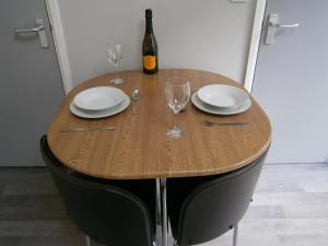 a wooden table with plates and glasses and a bottle of wine at The Barn - Ilkeston- Close to M1-A52 Long Eaton - Nottingham - Derbyshire - 500Mbs WiFi! in Ilkeston