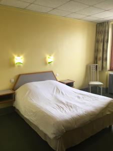 een slaapkamer met een wit bed met 2 verlichting aan de muur bij Hostellerie d'Alsace in Cernay