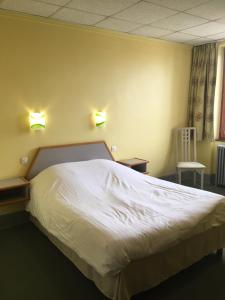 a bedroom with a white bed with two lights on the wall at Hostellerie d'Alsace in Cernay