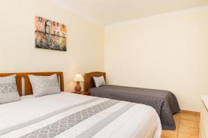 a bedroom with two beds and a picture on the wall at HouseLuz in Armação de Pêra