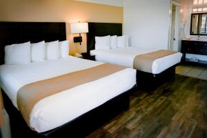 Postel nebo postele na pokoji v ubytování Pines Inn & Suites
