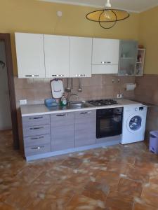 een keuken met witte kasten, een wastafel en een vaatwasser bij Villa Simone in Pachino