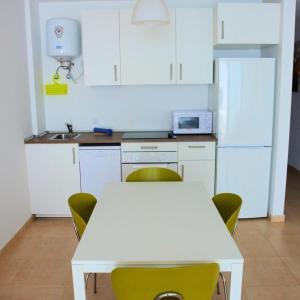 a white kitchen with a white table and chairs at Casa Mate Cotillo Mar in El Cotillo