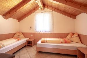 Duas camas num quarto com tectos em madeira em Haus Winkler em Vilpiano