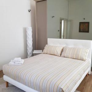 a bedroom with a white bed with a striped blanket at DE PIANTE GUEST in Busto Arsizio