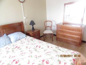 a bedroom with a bed and a chair and a window at Casa Benarus in Angra do Heroísmo