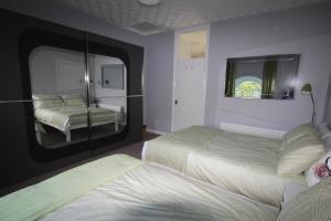 a bedroom with two beds and a mirror at Mullarts Church Apartments - The Glencorp Apartment in Knocknacarry
